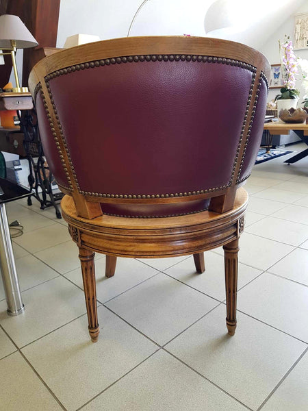 Fauteuil pivotant de style Louis XVI en bois de noyer et cuir clouté