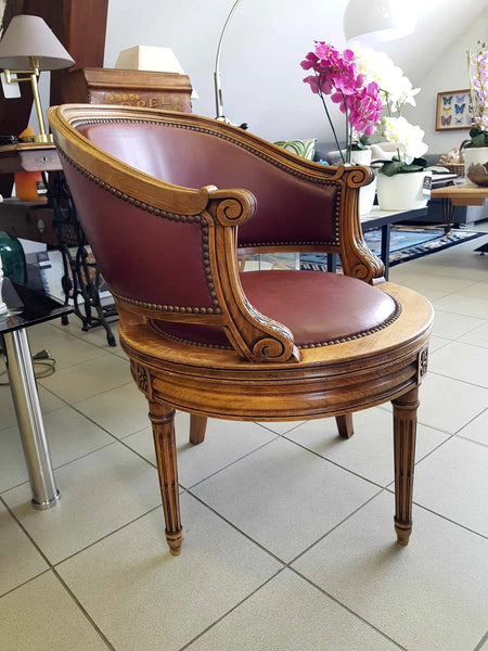 Fauteuil pivotant de style Louis XVI en bois de noyer et cuir clouté