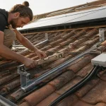Panneaux solaires sur toiture : artisan vérifie surimposition et étanchéité